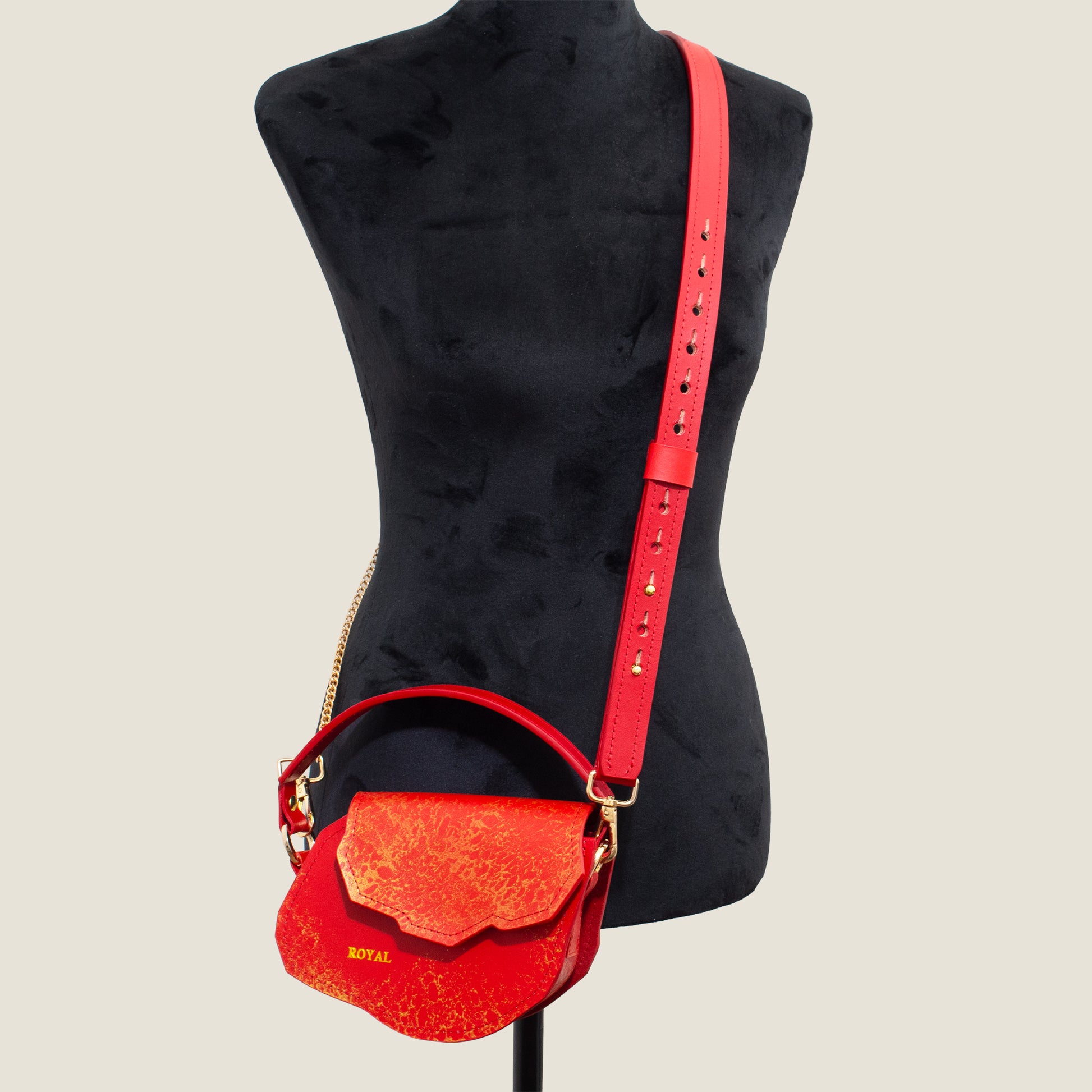 Charity hand‑painted full‑grain leather mini crossbody in red with gold accents on a mannequin with its chain strap.  