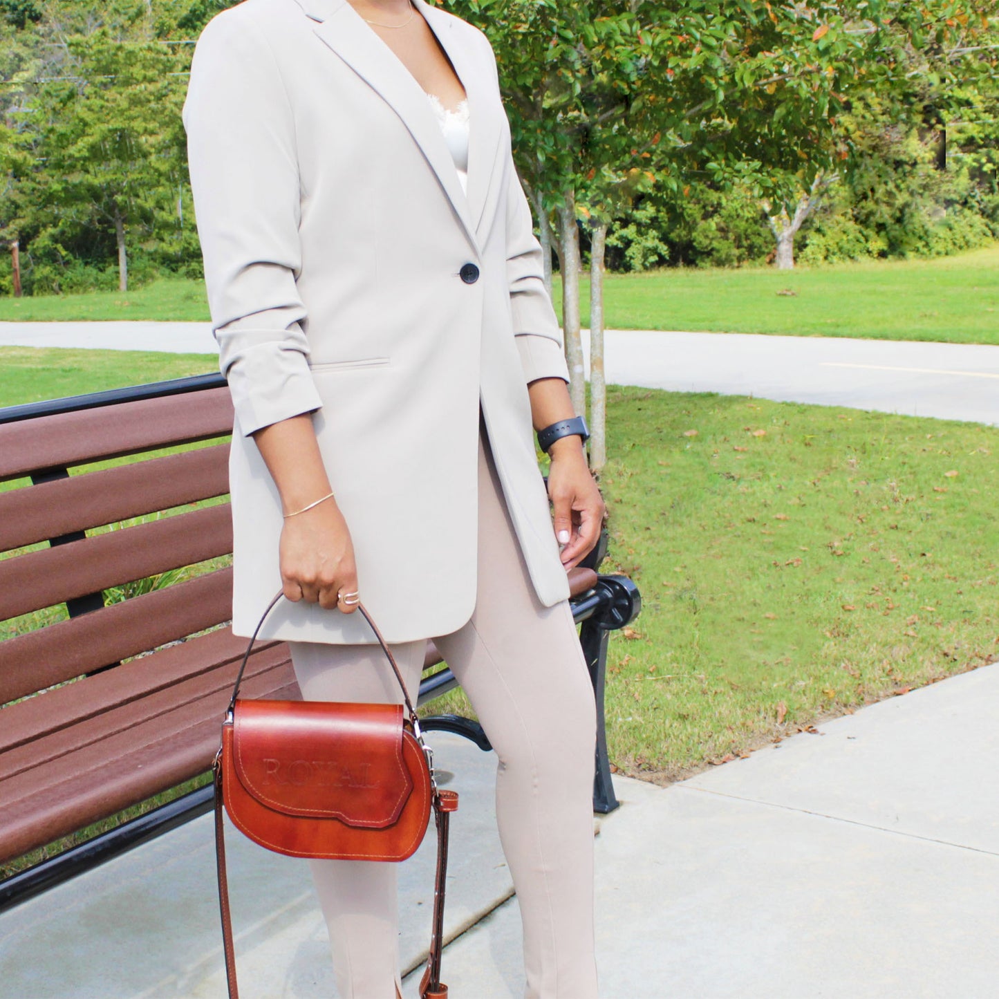 Hand‑painted full‑grain leather Grace top‑handle crossbody bag handcrafted in brown, held by a woman with its attached full‑grain leather strap.  