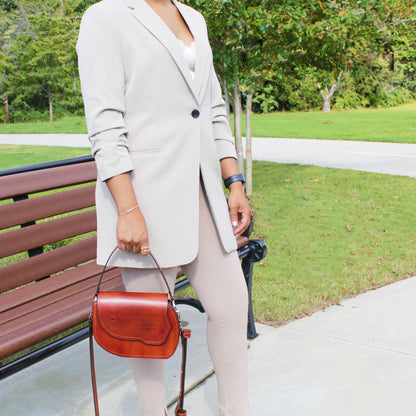 Hand‑painted full‑grain leather Grace top‑handle crossbody bag handcrafted in brown, held by a woman with its attached full‑grain leather strap.  