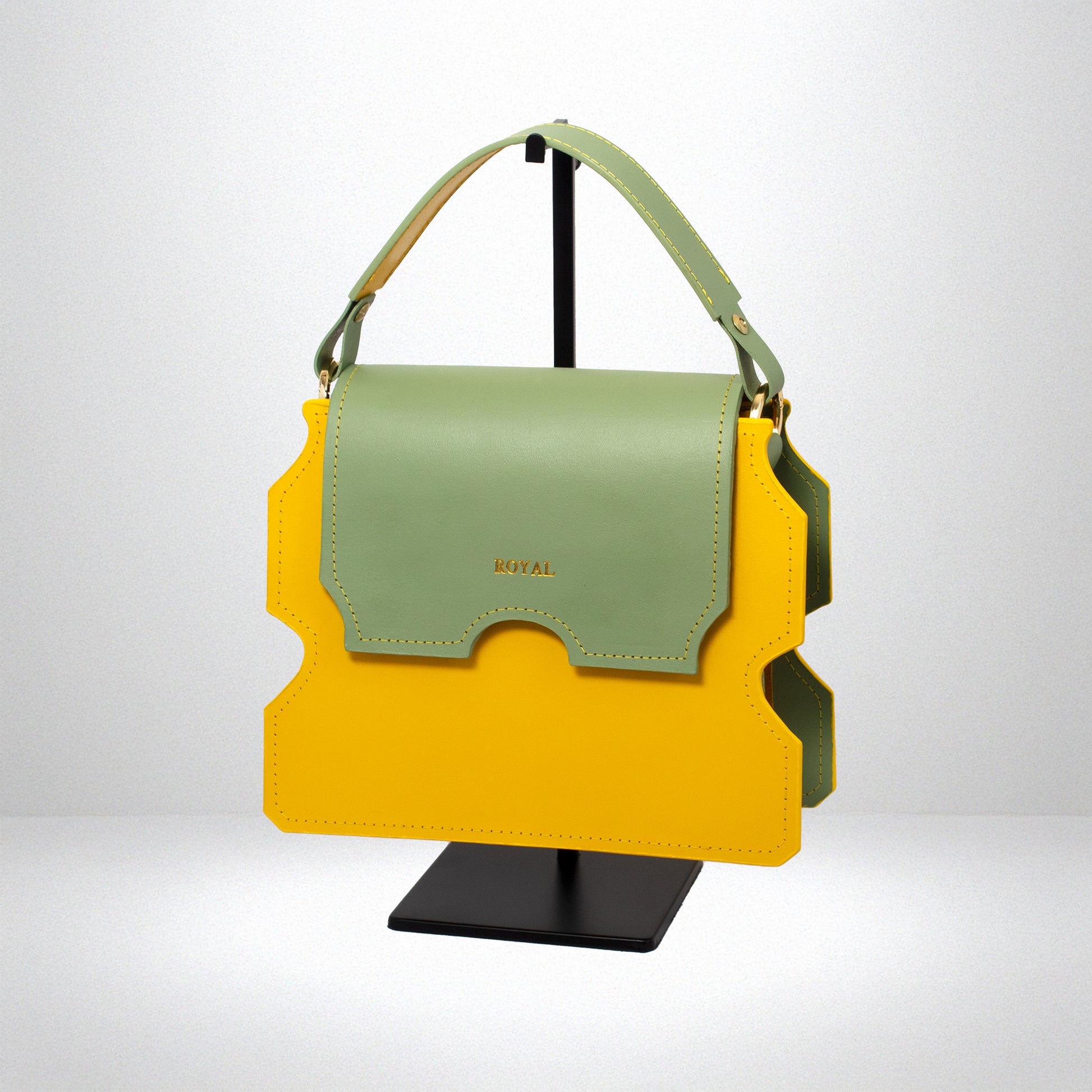 Hand-painted full-grain leather Faith shoulder bag bespoke in yellow with a pastel mint green flap, shown in a slanted side view on a stand.  