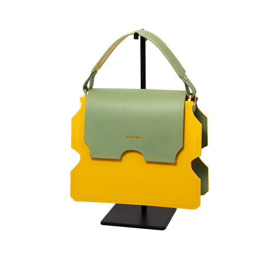 Hand-painted full-grain leather Faith shoulder bag custom-made in yellow with a pastel mint green flap, shown in a front view on a stand with its top handle.  