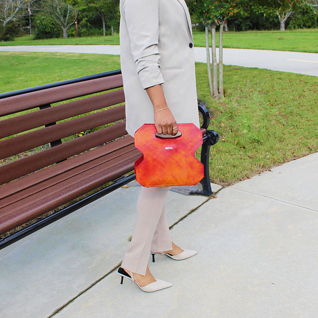 Hand‑painted full‑grain leather Miracle cut‑out handle bag handcrafted in red with artisan multi‑tone accents, held by a woman to highlight the design.  
